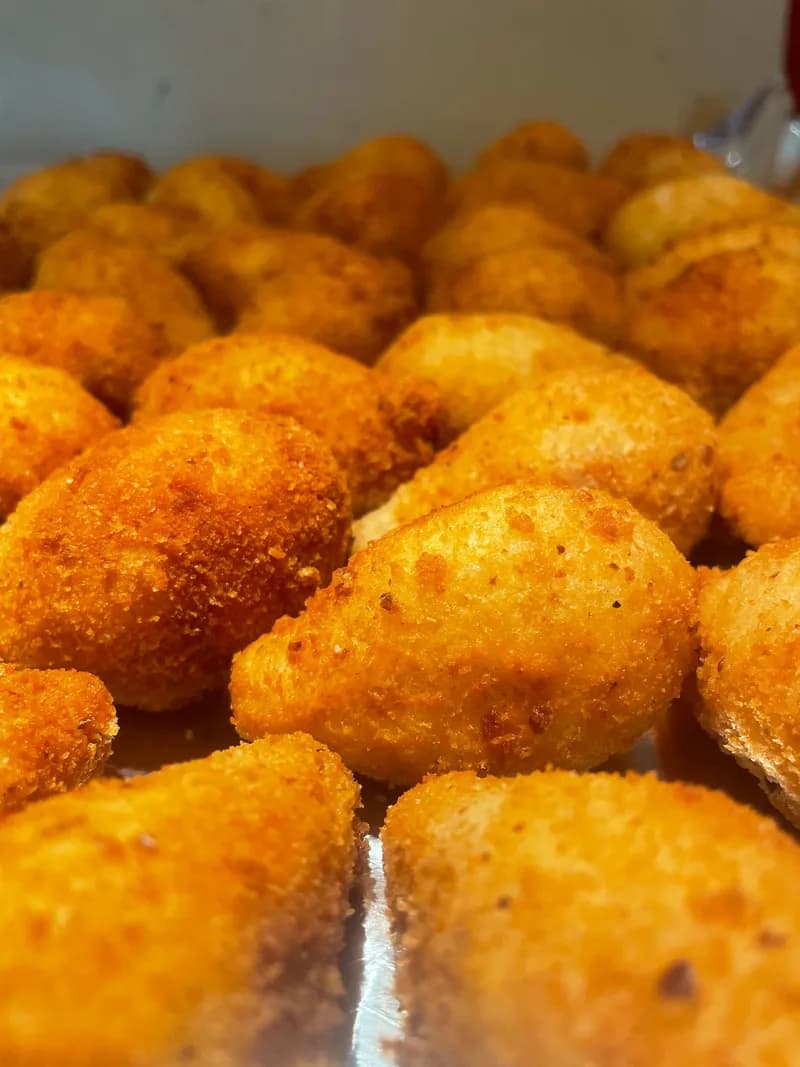 Golden teardrop-shaped coxinhas piled on a tray