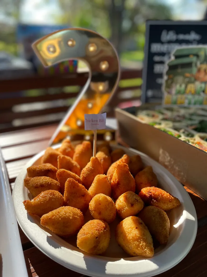 A white platter of coxinhas labelled Chicken Bite, in front of a lit number two for a birthday